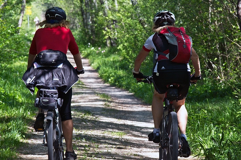 Två personer cyklar mountainbike i naturen.