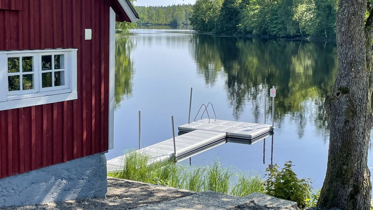 En röd bastustuga med ett picknickbord och utsikt över Eseredssjön.